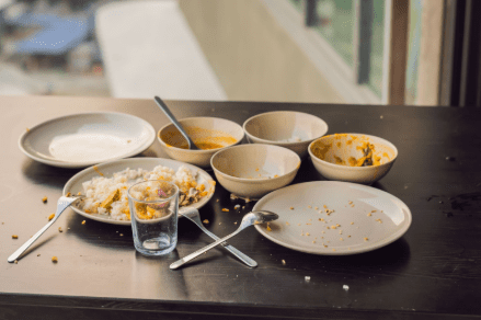 A close-up view of a messy dining table with used plates and cutlery